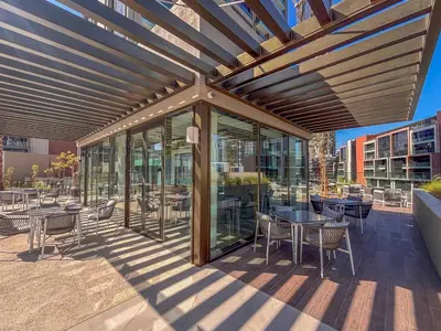 a covered patio with tables and chairs and windows at Frank Porter - Peninsula Five in Dubai