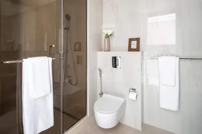 a bathroom with a toilet and a shower with towels at Frank Porter - Peninsula Five in Dubai