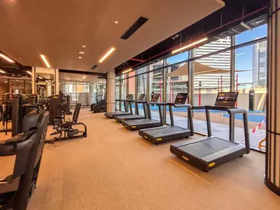 a gym with a row of treadmills and a pool at Frank Porter - Peninsula Five in Dubai
