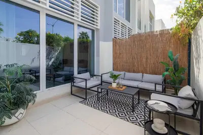 a patio with a couch and chairs on a balcony at Frank Porter - Avencia 44 in ‘Ūd al Bayḑāʼ