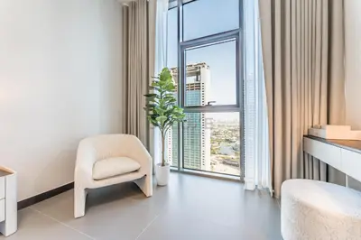 a room with a chair and a large window at High-Rise 1BR with Lake and City Views and Minutes to Metro, MBL Royal, Jumeirah Lake Towers by Deluxe Holiday Homes in Dubai