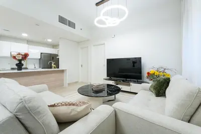 a living room with two white couches and a tv at Veluxa - Renovated 1BHK next to Golf in Dubai