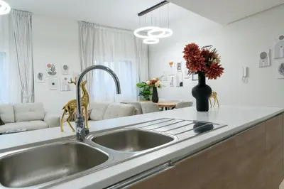 a kitchen with a sink and a living room at Veluxa - Renovated 1BHK next to Golf in Dubai