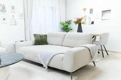 a white living room with a couch and a table at Veluxa - Renovated 1BHK next to Golf in Dubai