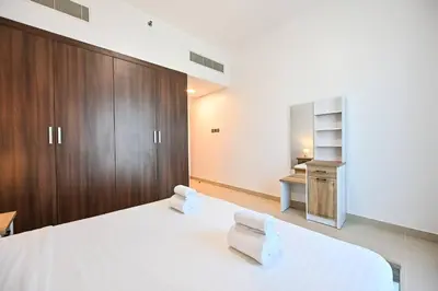 a bedroom with a large white bed and wooden cabinets at Stylish 1BR Apartment - Central Location in JVC - Balcony - Holiday Boulevard in Dubai