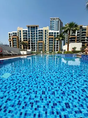 a large blue swimming pool with buildings in the background at Azizi Rivera 33 in Dubai
