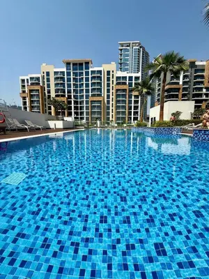 a large blue swimming pool with buildings in the background at Azizi Riviera 43 in Dubai