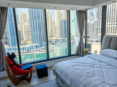 a bedroom with a large window with a bed and a chair at Nomad Retreats- Silverene tower Marina view in Dubai