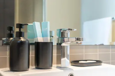 a bathroom counter with two bottles of soap and a mirror at Silverene Tower - One Bedroom By Home Of Choice in Dubai