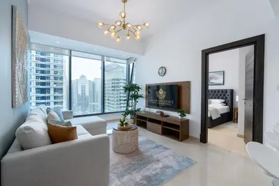 a living room with a couch and a large window at Silverene Tower - One Bedroom By Home Of Choice in Dubai