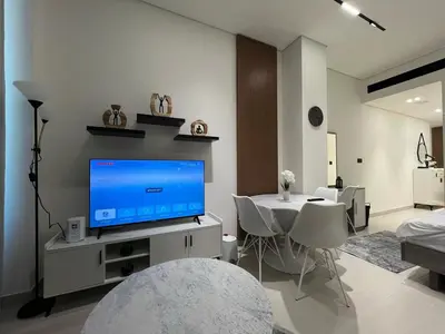 a living room with a tv and a table with chairs at Luxury - Burj Khalifa View - Private Jacuzzi in Dubai