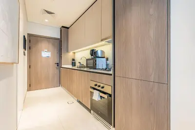 a small kitchen with wooden cabinets and a microwave at Near Dubai Miracle Garden Studio with Community Views Balcony, Legacy by Sunrise, Arjan-Dubailand by Deluxe Holiday Homes in Dubai