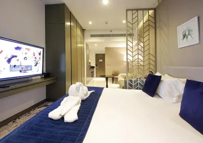 a white stuffed animal sitting on a bed in a room at Stylish Studio Apartment in Dubai with Pool & Gym in Dubai
