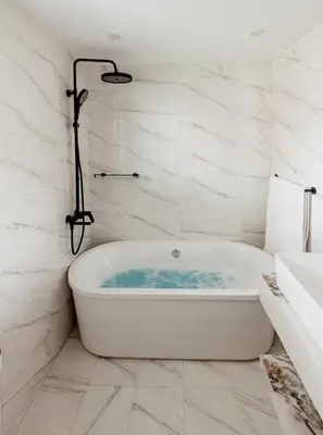 a bath tub in a bathroom with white marble walls at Beautiful 3 bed In Dubai Marina! in Dubai