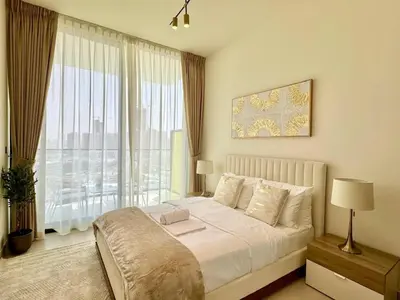 a bedroom with a bed and a large window at Bright & Modern 1br In Jvc Pool Free Parking in Dubai