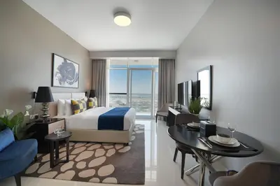a hotel room with a bed and a table and chairs at EasyGo- Sleek Studio at Damac Hills Artesia D in Dubai