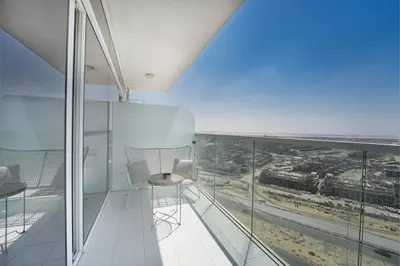 a room with a balcony with a view of the ocean at EasyGo- Sleek Studio at Damac Hills Artesia D in Dubai