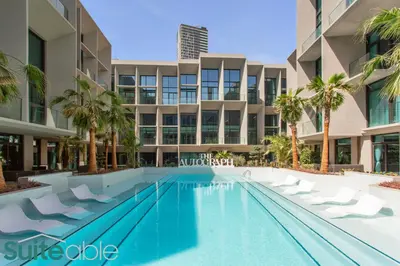a swimming pool in front of a building with palm trees at Vibrant & Exclusive Pool View Studio in Autograph in Dubai