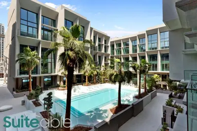 an apartment building with a swimming pool and palm trees at Vibrant & Exclusive Pool View Studio in Autograph in Dubai