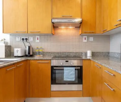 a kitchen with wooden cabinets and a stainless steel oven at Business Bay Mahek Holiday Home in Dubai