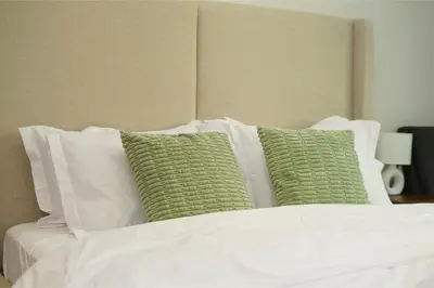 a bed with white sheets and green pillows at PurityStaysDXB in Dubai