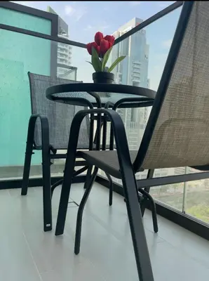 a table and chairs on a balcony with a vase of flowers at PurityStaysDXB in Dubai