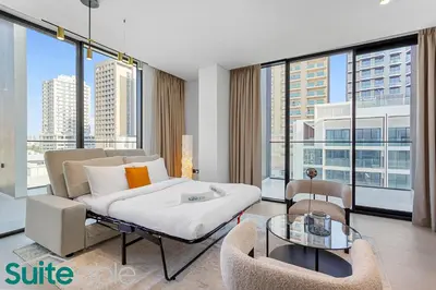 a living room with a bed and chairs and windows at Sophisticated 1 Bedroom in Binghatti Galaxy JVC in Dubai
