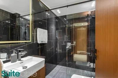 a black tiled bathroom with a sink and a shower at Sophisticated 1 Bedroom in Binghatti Galaxy JVC in Dubai