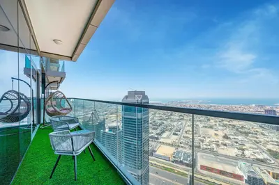 a balcony with two chairs on the top of a skyscraper at 3 Bedroom - Pool Access - 7 mins to Dubai Mall - Sun Set View in Dubai