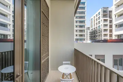 a balcony with a white table and some buildings at Elegant 1BR with Pool, Gym Access and Kid's Play Area in Dubai