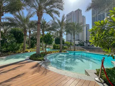 a swimming pool with palm trees in a city at Elegant 1BR with Pool, Gym Access and Kid's Play Area in Dubai