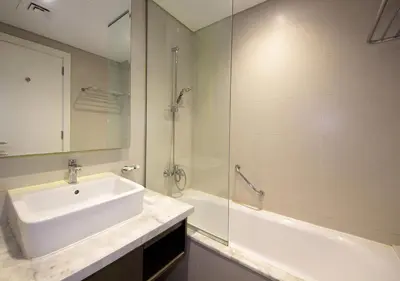 a white bathroom with a sink and a shower at Burj Khalifa & Canal View LuxeStudio in DAMACPrive in Dubai