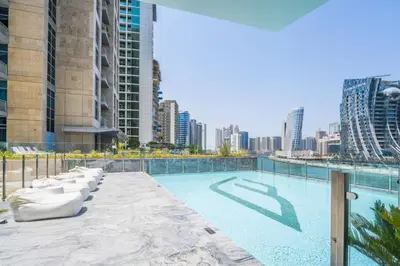 a swimming pool with chairs and a city skyline at Luxurious One Bed Near Dubai Mall with Burj and Canal View in Dubai