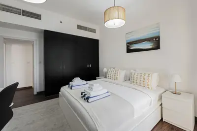 a bedroom with a large white bed with towels on it at Short Stay Apartment Shams 1 Jumeirah Beach Residence 2 Bed Sleeps 6 - DVH HOLIDAY HOMES in Dubai