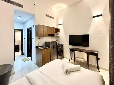 a bedroom with a bed and a desk and a kitchen at Al Manara Classic Cozy Studio in Dubai