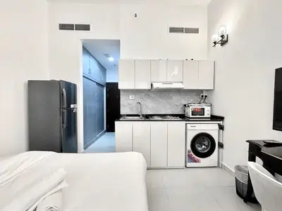 a white kitchen with a stove and a refrigerator at Al Manara Classic Deluxe Studio in Dubai