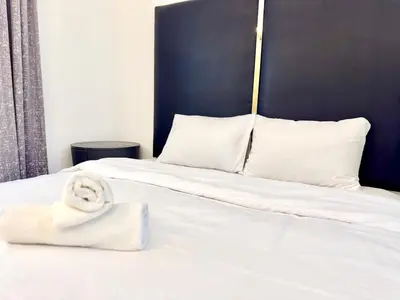 a bed with white sheets and a towel on it at Al Manara Classic Deluxe Studio in Dubai