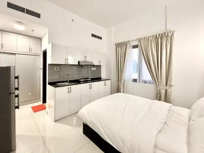 a white bedroom with a bed and a kitchen at Al Manara Classic Executive Studio in Dubai