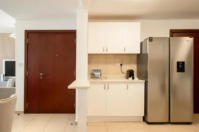 a kitchen with a stainless steel refrigerator and white cabinets at JBR Rimal By Luxe Living - Dubai Eye View in Dubai