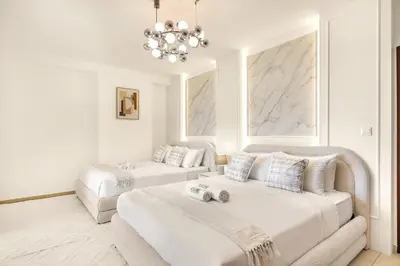 a white room with two beds and a chandelier at JBR Rimal By Luxe Living - Dubai Eye View in Dubai