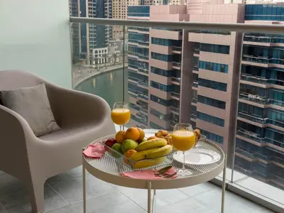 a table with a bowl of fruit and two glasses of orange juice at Appartement Moderne Dubai Marina in Dubai