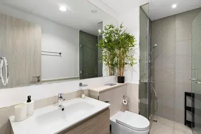 a bathroom with a sink and a toilet and a mirror at Stylish 1BR In Zada Tower With Pool Views in Dubai
