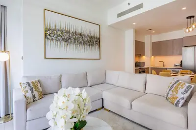 a living room with a white couch and a vase of flowers at Act One Act Two - Sophisticated Two Bedroom in Dubai