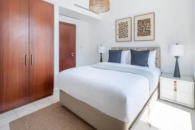 a white bedroom with a large bed with blue pillows at Frank Porter - Al Yass Tower in Dubai