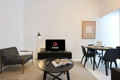 a living room with a tv and chairs and a table at Livbnb-Spacious 2 BR in Dubai Marina with Balcony in Dubai