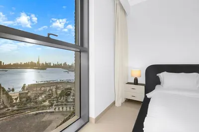 a bedroom with a window with a view of the city at FIRST CLASS 2BR Creek Harbour & Burj Views in Dubai