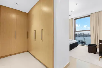a bedroom with wooden cabinets and a view of the water at FIRST CLASS 2BR Creek Harbour & Burj Views in Dubai