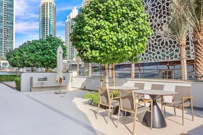 a patio with a table and chairs and a tree at FIRST CLASS 2BR Burj Khalifa & Fountain view in Dubai