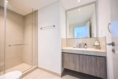 a bathroom with a shower and a sink and a mirror at Burj Khalifa View, Luxury Two-Bedroom Residence, PlayStation 5, Swimming Pool and Fitness Center in Dubai