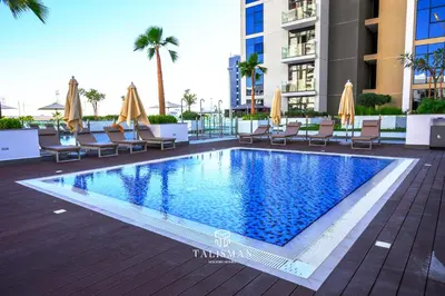 a swimming pool with chairs and umbrellas on a building at Modern Studio in Azizi Riviera, Meydan in Dubai